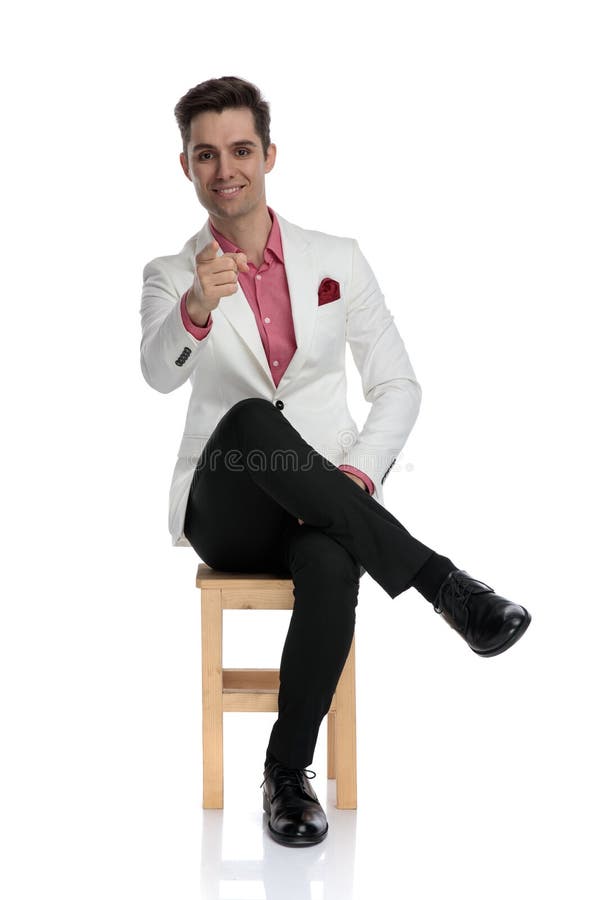 Seated elegant man is pointing finger at the camera