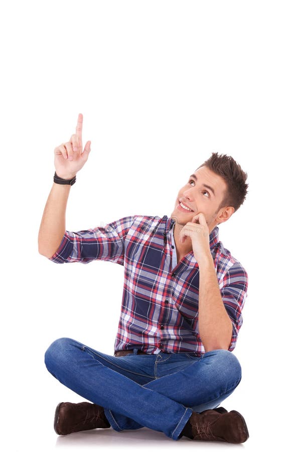 Seated young casual man pointing at something up stock images