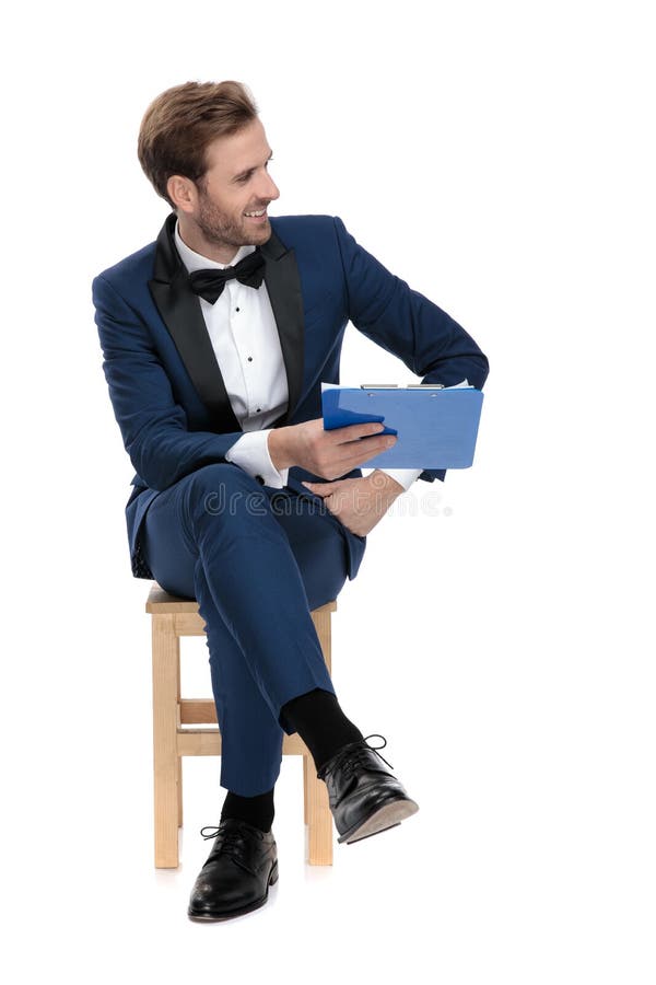Seated young guy in blue suit giving his clipboard royalty free stock photos Seated young guy in blue suit giving his clipboard royalty free stock photos
