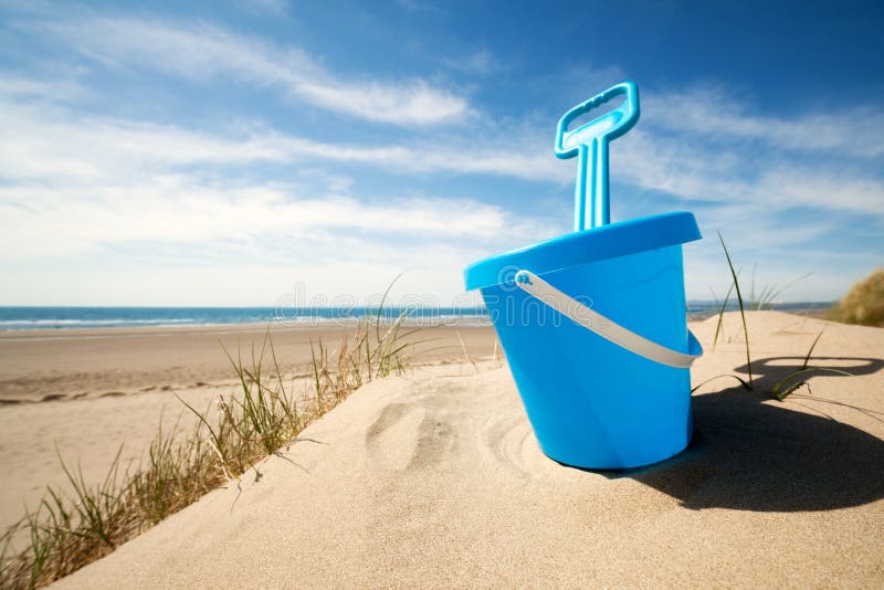 Childs bucket and spade or sand pail and shovel at the beach on a sunny summer day. Childs bucket and spade or sand pail and shovel at the beach on a sunny summer day