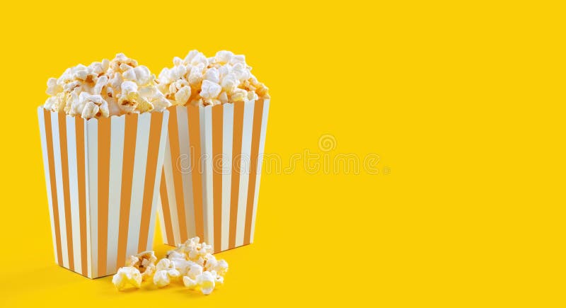 Secchio di cartone arancione a strisce bianche con popcorn di formaggio saporito isolato sullo sfondo giallo fotografia stock libera da diritti