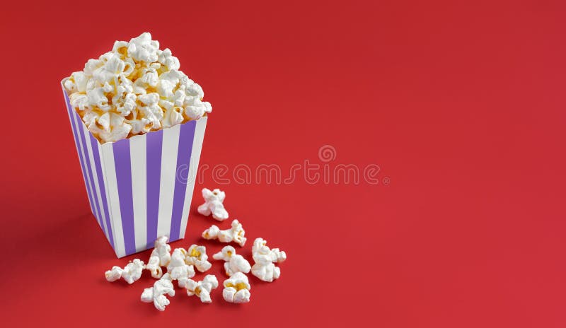 Secchio di cartone a strisce bianche con formaggio gustoso popcorn isolato su fondo rosso fotografia stock libera da diritti