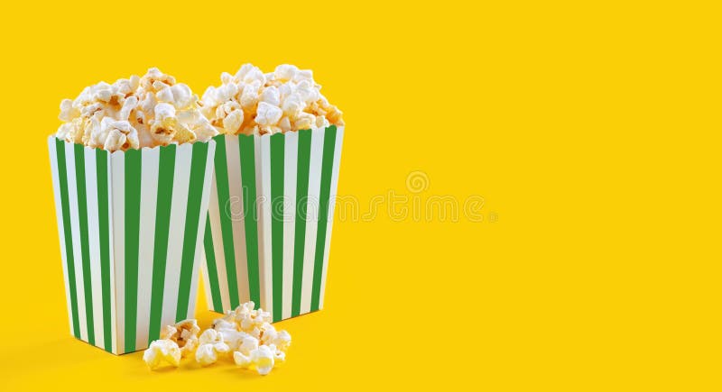 Secchio di cartone a strisce verdi bianco con popcorn di formaggio saporito isolato su fondo giallo immagine stock