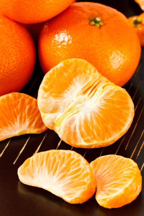 Close up overhead view of fresh, healthy whole and peeled mandarin oranges against a black background. Close up overhead view of fresh, healthy whole and peeled mandarin oranges against a black background