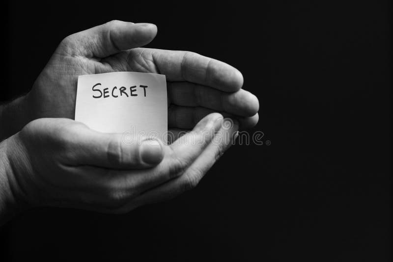 Hands covering up a secret. The word secret printed on a card. Hands covering up a secret. The word secret printed on a card.