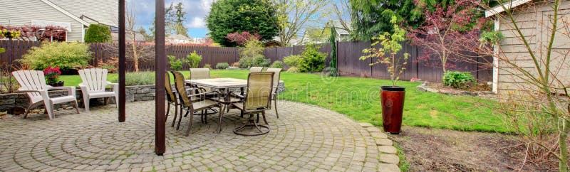 Cozy backyard ared with stoned floor, patio table set and white chairs. Cozy backyard ared with stoned floor, patio table set and white chairs