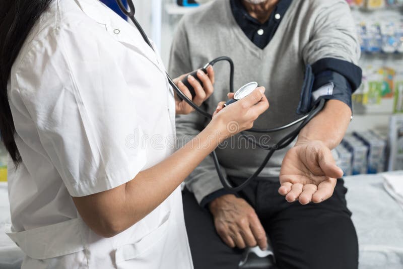 Section médiane de tension artérielle du ` s de Checking Patient de chimiste photo stock Section médiane de tension artérielle du ` s de Checking Patient de chimiste photo stock