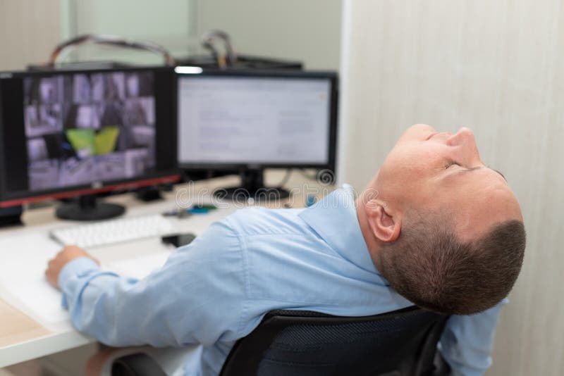Security guard sleeping at workplace in surveillance room stock photo