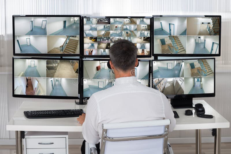 Security System Operator Looking At CCTV Footage At Desk stock photography
