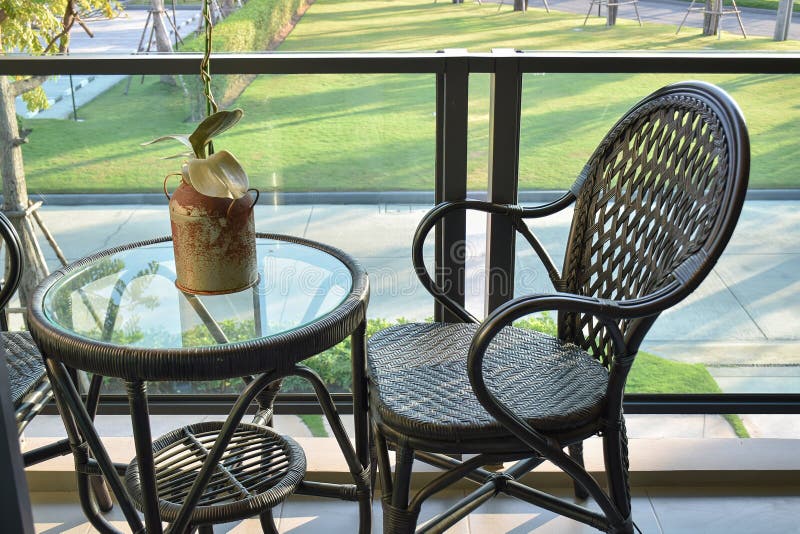 Sedia del rattan di Brown sul balcone che trascura un giardino fotografia stock