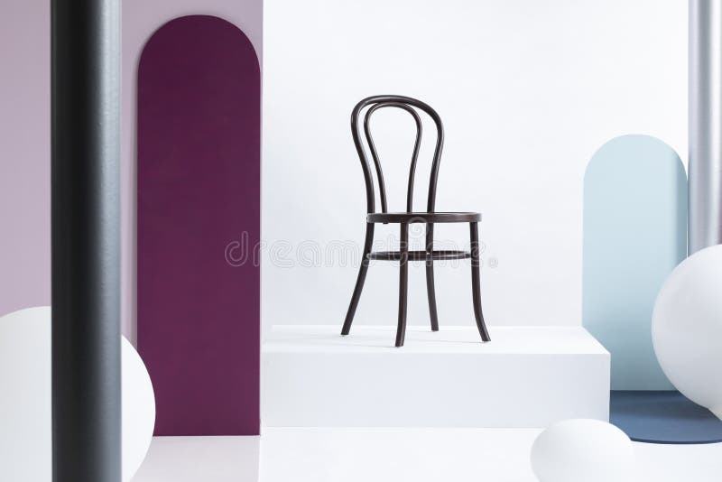 Sedia di legno marrone alla moda sulla piattaforma bianca nell'interno della sala d'esposizione con i grandi palloni e le pareti immagine stock libera da diritti