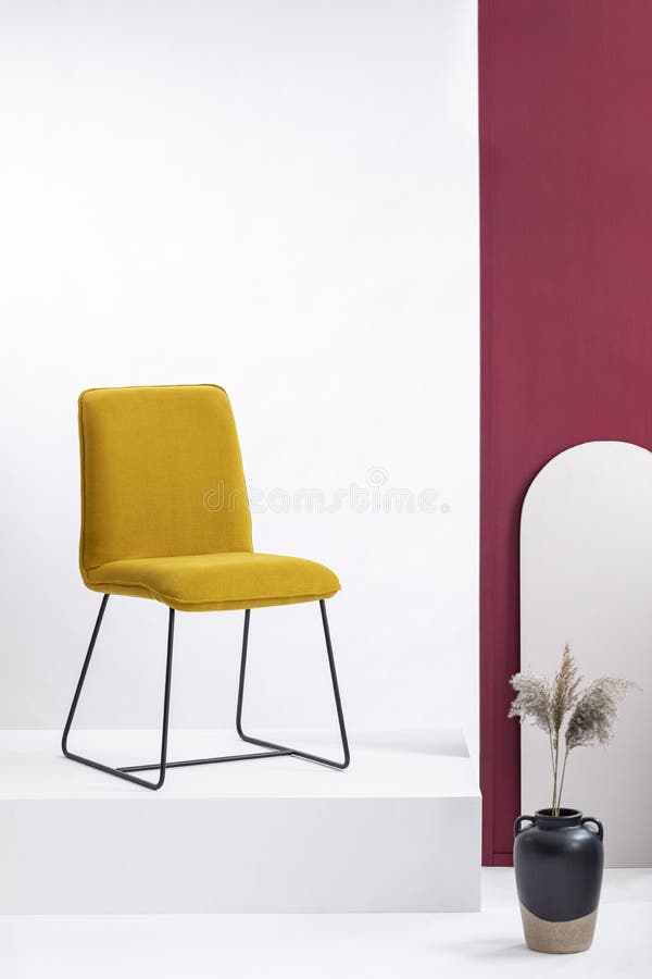 Sedia gialla alla moda sulla piattaforma bianca in sala d'esposizione elegante con le pareti bianche e porpora immagine stock