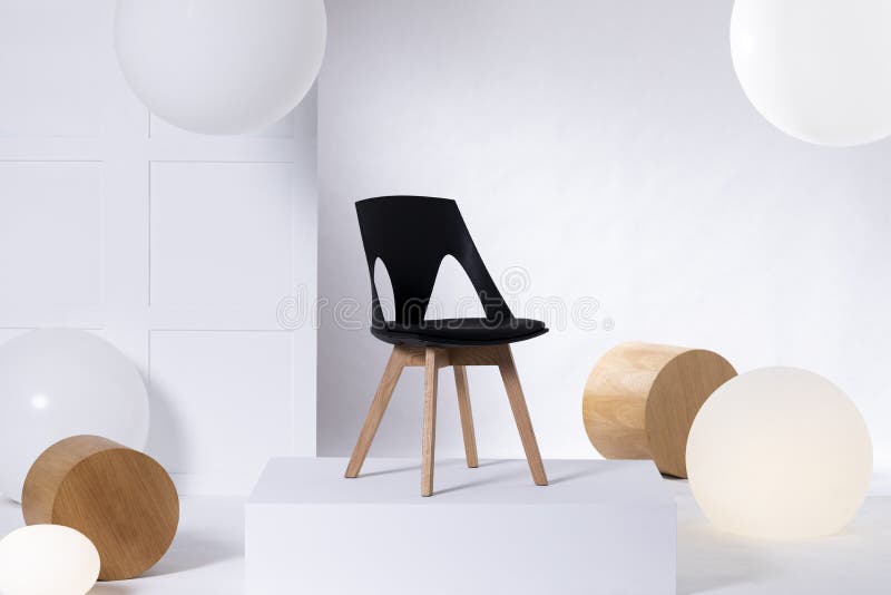 Sedia nera alla moda sulla piattaforma bianca in sala d'esposizione luminosa interna con i grandi palloni ed i blocchi di legno fotografie stock