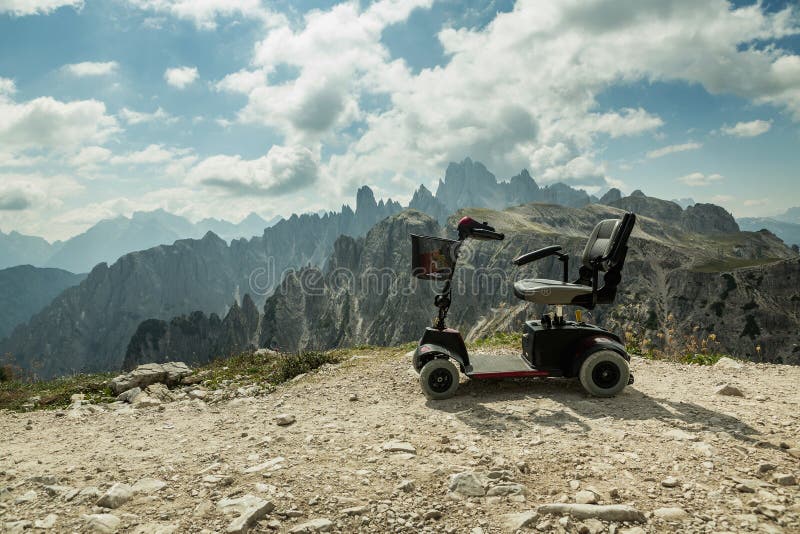 Sedia a rotelle motorizzata per la gente eliminabile, carrozzini elettrici mobili sulla montagna, dolomia, Italia fotografia stock libera da diritti Sedia a rotelle motorizzata per la gente eliminabile, carrozzini elettrici mobili sulla montagna, dolomia, Italia fotografia stock libera da diritti