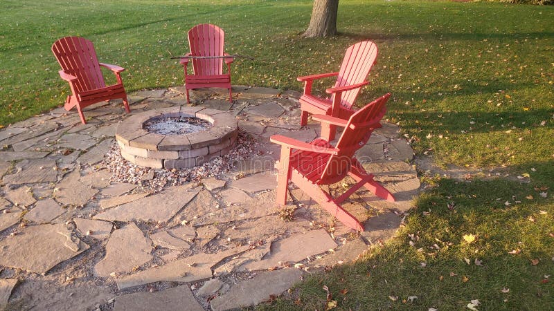 4 aderondic chairs sitting around a un-lit stone campfire pit at sunset. 4 aderondic chairs sitting around a un-lit stone campfire pit at sunset