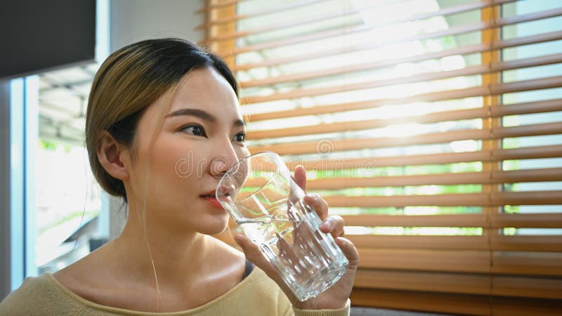 Sedienta mujer asiática tomando agua fresca y pura refrescante durante el día. concepto de estilo de vida saludable e hidratación foto de archivo libre de regalías
