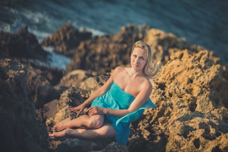 Seductive Blond Lady Woman with Naked Legs Shoulders and Arms Wearing Light Blue Open Dress Posing Enjoying Vacation Time on Stock Image