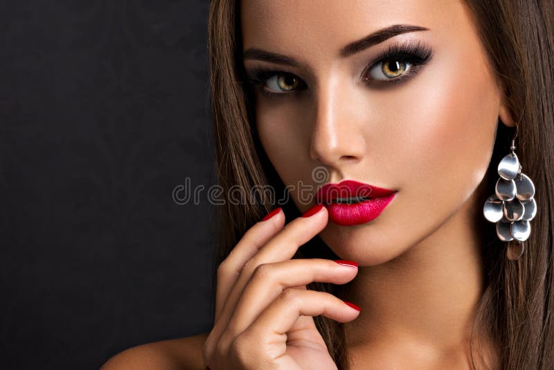 Seductive woman with dark brown eye makeup and bright red lips and nails