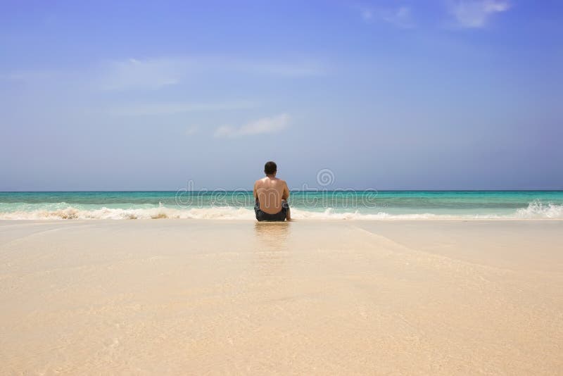 Seduta dell'uomo sola sulla spiaggia immagini stock libere da diritti Seduta dell'uomo sola sulla spiaggia immagini stock libere da diritti