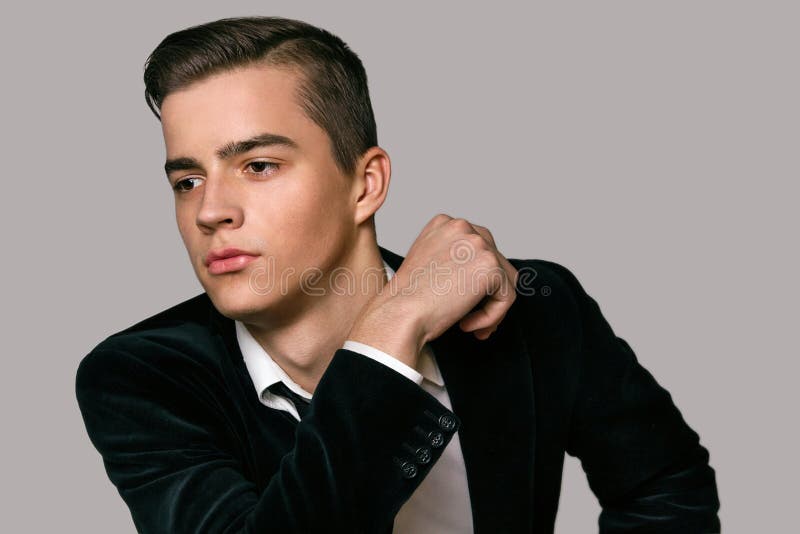 Seduta di modello maschio in uno studio del nero del vestito fotografie stock libere da diritti Seduta di modello maschio in uno studio del nero del vestito fotografie stock libere da diritti