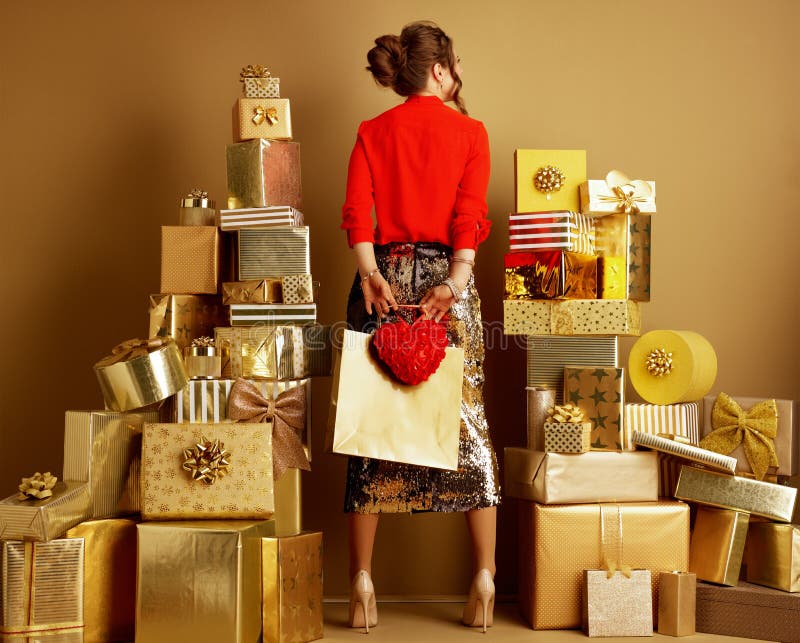 Seen from behind trendy woman with shopping bag and red heart