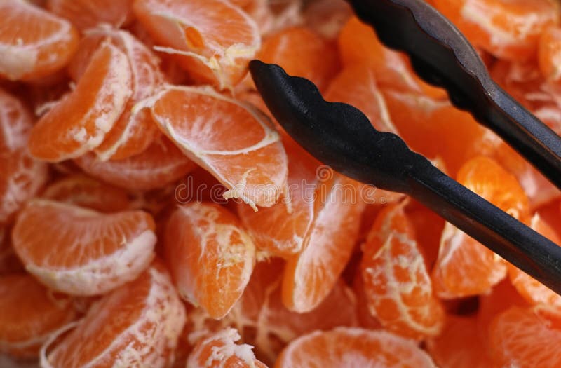 Segmentos da tanjerina e tenazes de brasa pretos imagens de stock Segmentos da tanjerina e tenazes de brasa pretos imagens de stock