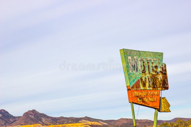 Vintage Rusted Metal Motel Sign With Mountains & Mining Operations In Background. Vintage Rusted Metal Motel Sign With Mountains & Mining Operations In Background