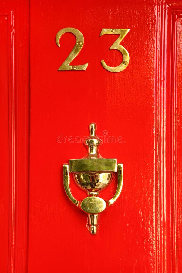 Golden sign on red wooden door; 23 and cup; reflection in cup. Golden sign on red wooden door; 23 and cup; reflection in cup