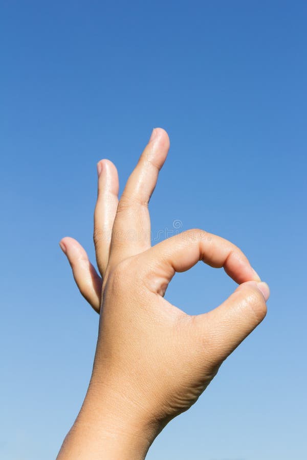 Segno giusto della mano sul fondo del cielo immagine stock Segno giusto della mano sul fondo del cielo immagine stock