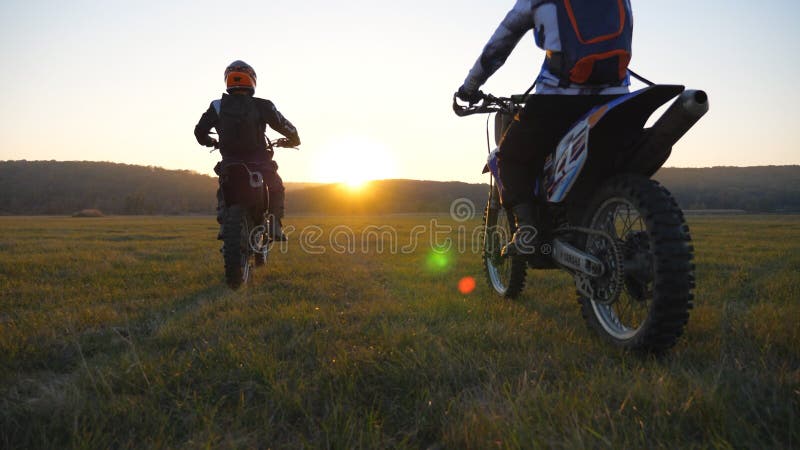 Seguimento di una telecamera da parte di motociclisti che attraversano il campo con motociclette. amici con riposo attivo che guid