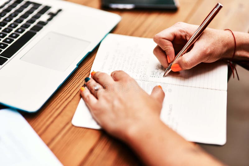 Tracking my expenses. Cropped shot of an unrecognizable businesswoman sitting alone and writing in her notebook during the day. Tracking my expenses. Cropped shot of an unrecognizable businesswoman sitting alone and writing in her notebook during the day