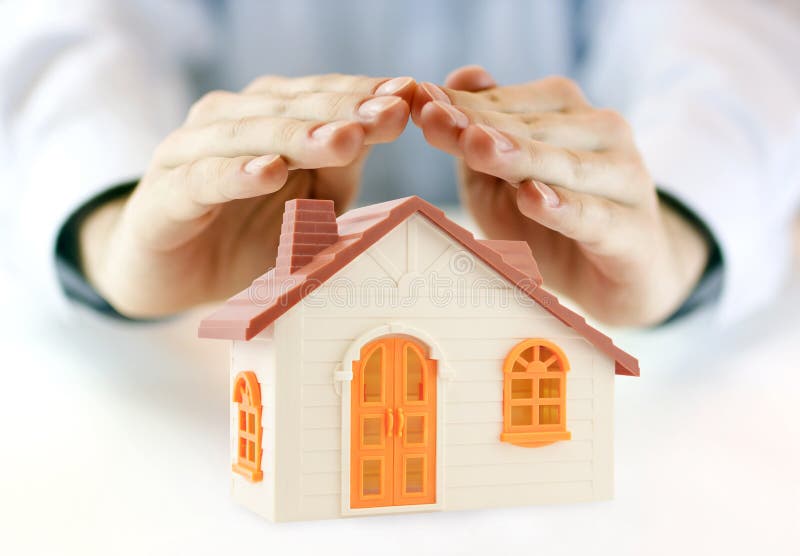 Small orange toy house covered by hands. Small orange toy house covered by hands