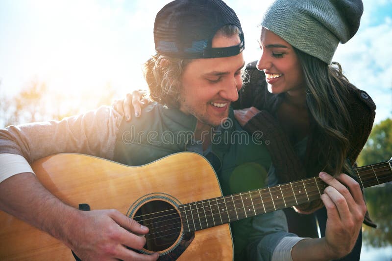 Seguro que sabe cómo hacerme sentir especial. un joven tocando una canción a su novia en su guitarra.