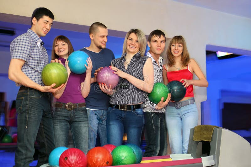 Sei amici si levano in piedi e tiene le sfere per il bowling fotografia stock Sei amici si levano in piedi e tiene le sfere per il bowling fotografia stock