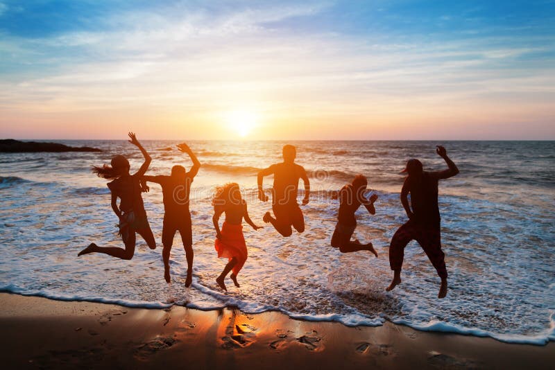 Seis Personas Que Saltan En La Playa En La Puesta Del Sol Imagen de