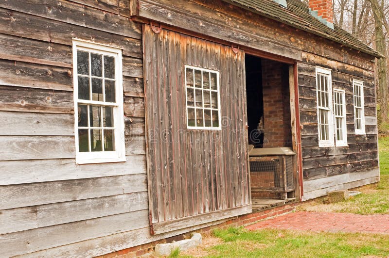 A view of the side of an old, antique, weather-beaten barn or shed with a sliding doorway. A view of the side of an old, antique, weather-beaten barn or shed with a sliding doorway.