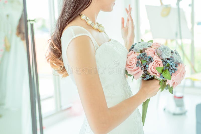 Seitenansicht der Braut hält einen Heiratsblumenstrauß und zeigt ihre Hochzeit stockfotografie Seitenansicht der Braut hält einen Heiratsblumenstrauß und zeigt ihre Hochzeit stockfotografie