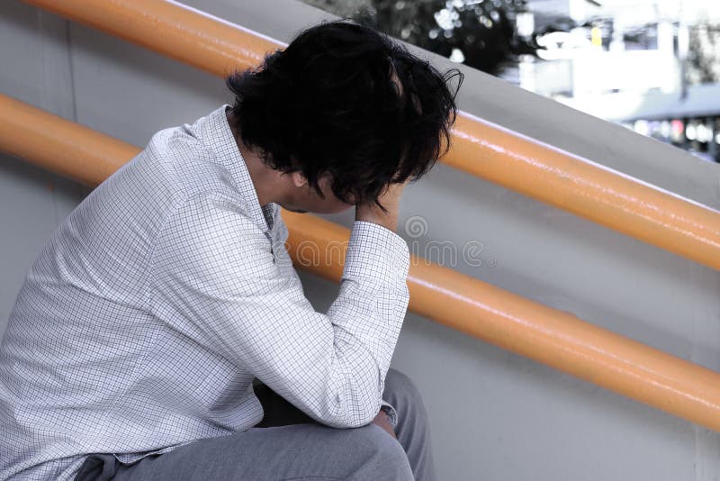 Seitenansicht des deprimierten betonten jungen asiatischen Geschäftsmannes mit den Händen, die Kopf berühren und enttäuscht oder lizenzfreies stockbild Seitenansicht des deprimierten betonten jungen asiatischen Geschäftsmannes mit den Händen, die Kopf berühren und enttäuscht oder lizenzfreies stockbild