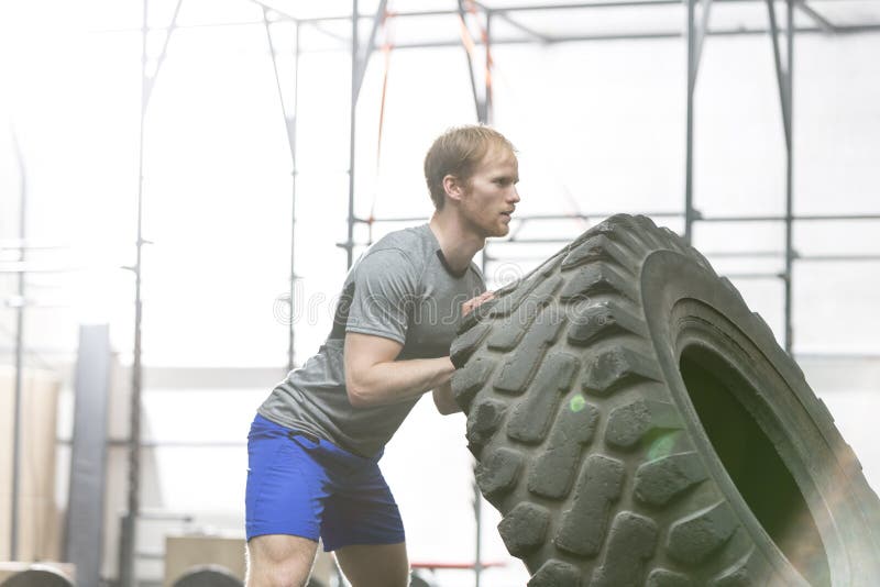 Seitenansicht des engagierten Mannes Reifen in crossfit Turnhalle leicht schlagend stockfoto Seitenansicht des engagierten Mannes Reifen in crossfit Turnhalle leicht schlagend stockfoto