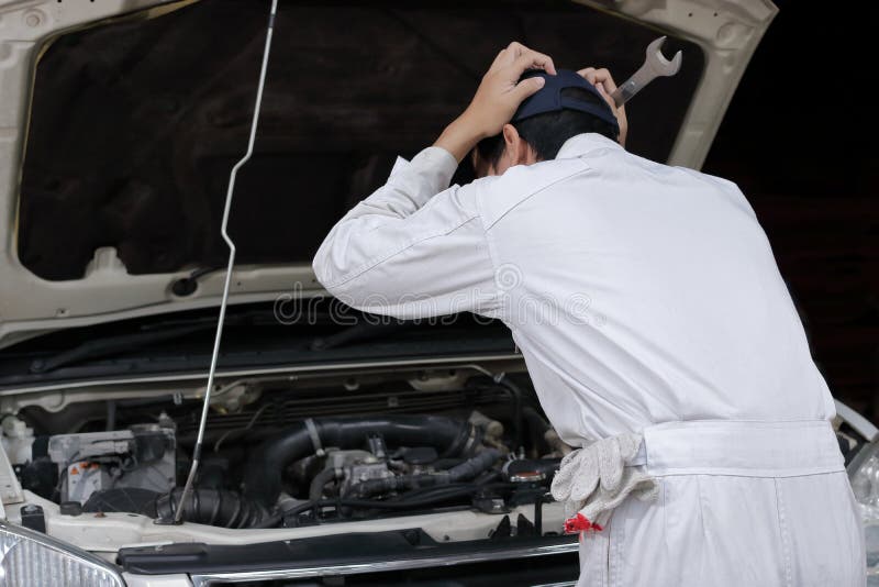 Seitenansicht des frustrierten betonten jungen Mechanikermannes in der weißen Uniform, die seinen Kopf mit den Händen gegen Auto lizenzfreies stockfoto Seitenansicht des frustrierten betonten jungen Mechanikermannes in der weißen Uniform, die seinen Kopf mit den Händen gegen Auto lizenzfreies stockfoto