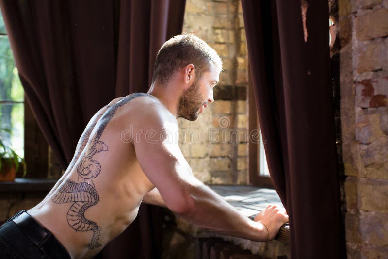Seitenansicht des Mannes mit tatoo auf seinem hinteren Handeln drücken ups