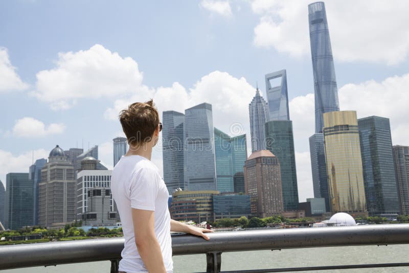 Seitenansicht des Mannes Shanghai-Weltfinanzzentrum betrachtend gegen bewölkten Himmel lizenzfreies stockfoto Seitenansicht des Mannes Shanghai-Weltfinanzzentrum betrachtend gegen bewölkten Himmel lizenzfreies stockfoto