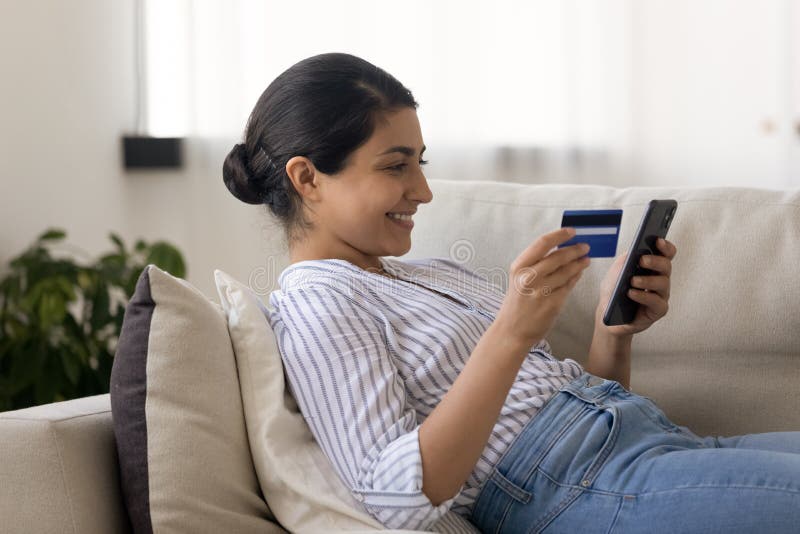 Seitenansicht lächelnde indische Frau online mit Kreditkarte zahlen lizenzfreies stockfoto