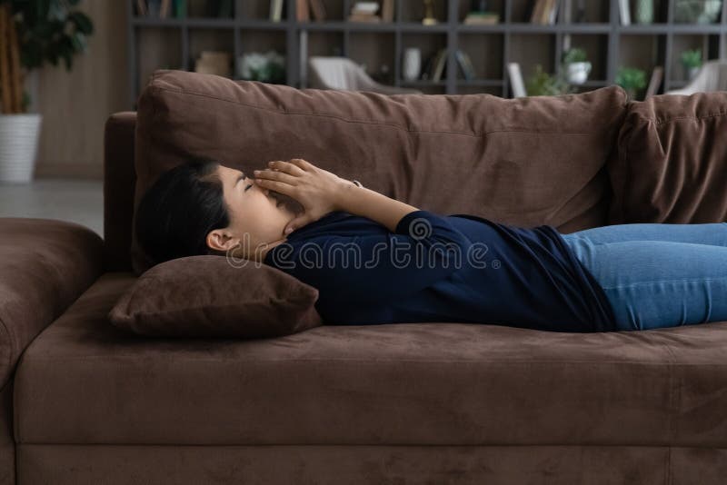 Seitenansicht unglückliche Inderin allein auf der Couch liegend lizenzfreie stockfotografie