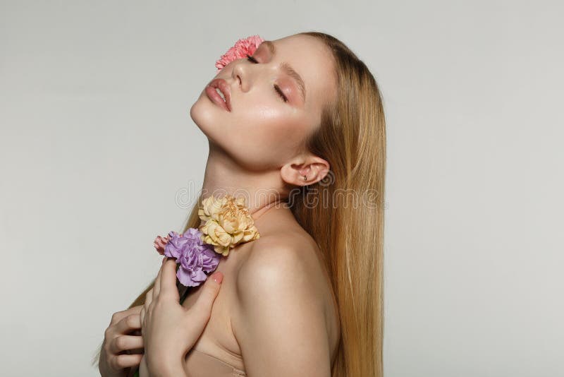Seitenansichtporträt des reizend jungen blonden Mädchens mit perfektem Make-up und geschlossenen Augen, drückte Blumen zu ihrem K stockfotografie Seitenansichtporträt des reizend jungen blonden Mädchens mit perfektem Make-up und geschlossenen Augen, drückte Blumen zu ihrem K stockfotografie