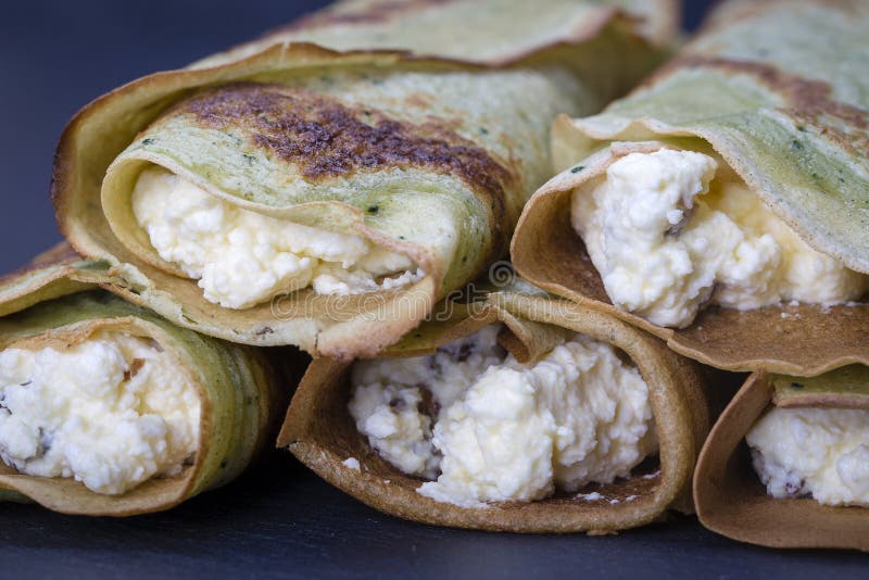 Selbst gemachte Pfannkuchen mit grünes spirulina angefülltem weißem Hüttenkäse mit Rosinen auf einem schwarzen Schieferhintergrun lizenzfreie stockfotografie Selbst gemachte Pfannkuchen mit grünes spirulina angefülltem weißem Hüttenkäse mit Rosinen auf einem schwarzen Schieferhintergrun lizenzfreie stockfotografie