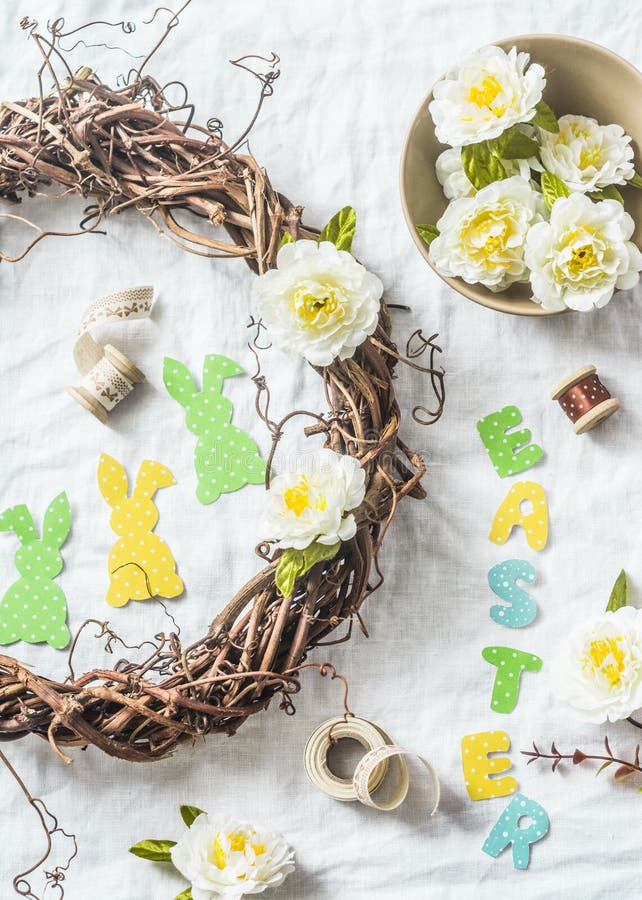 Selbst gemachten Ostern-Kranz von den Reben mit Blumen machend, tapezieren Sie Kaninchen, Bänder auf einem weißen Hintergrund, Dr stockfoto Selbst gemachten Ostern-Kranz von den Reben mit Blumen machend, tapezieren Sie Kaninchen, Bänder auf einem weißen Hintergrund, Dr stockfoto