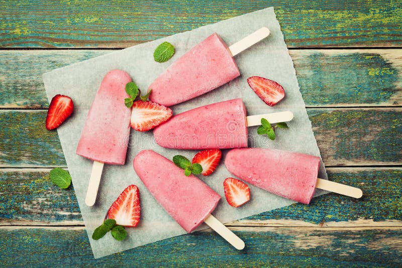 Selbst gemachter Erdbeereis oder Eis am Stiel auf rustikaler Tabelle, gefrorener Fruchtsaft, Draufsicht lizenzfreies stockbild