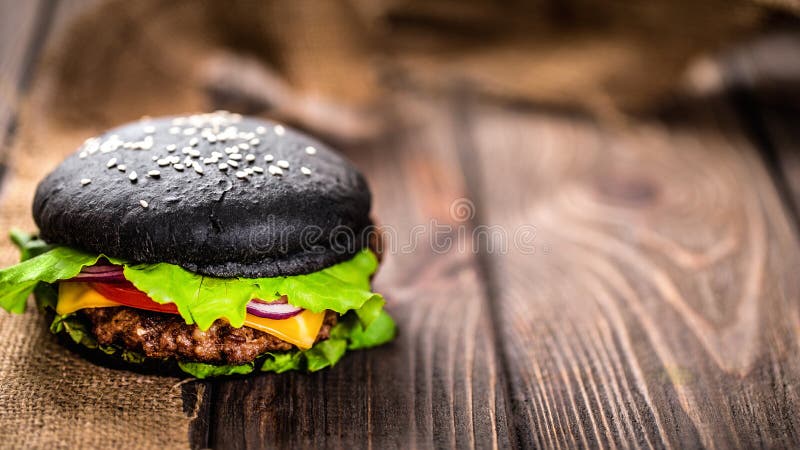 Selbst gemachter schwarzer Burger mit Käse Cheeseburger mit schwarzem Brötchen auf dunklem hölzernem Hintergrund stockfotografie Selbst gemachter schwarzer Burger mit Käse Cheeseburger mit schwarzem Brötchen auf dunklem hölzernem Hintergrund stockfotografie