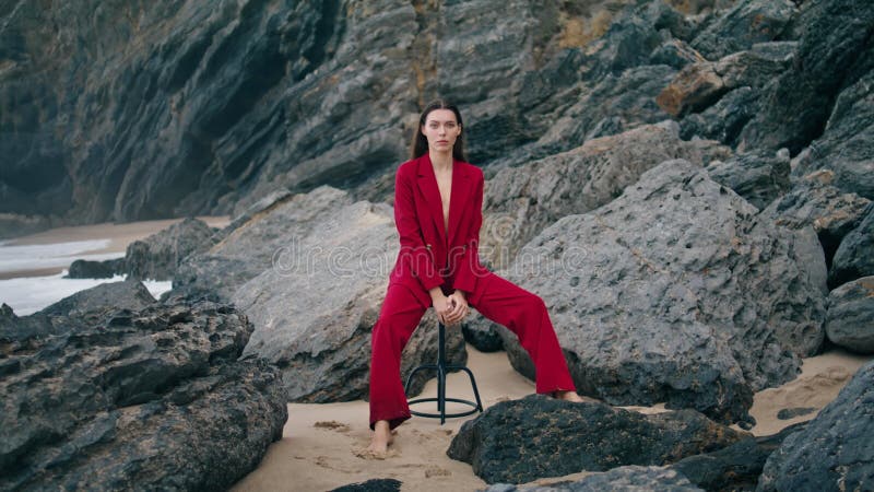 Selbstbewusstes Modell Sitzstuhl in der Natur Strandklippen mit sexy roten Anzug
